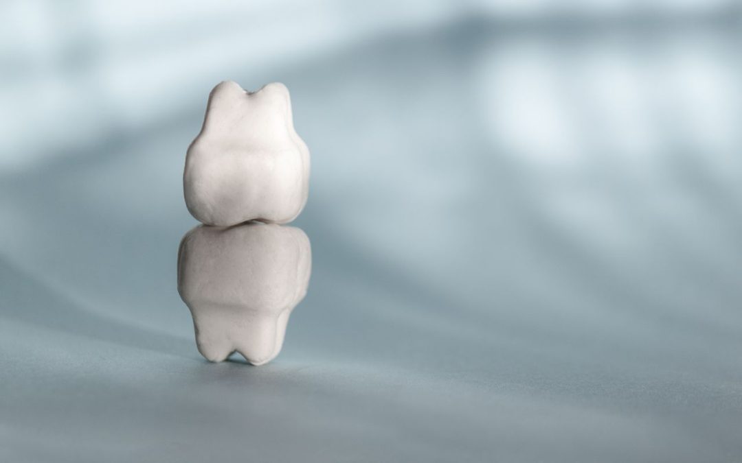 Modello di dente su sfondo sfocato, simbolo di salute dentale e trattamenti per il bruxismo.