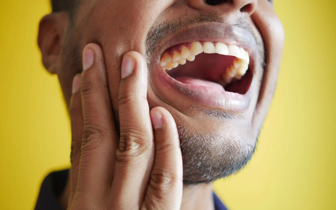 Uomo con dolore al dente che si tiene la guancia, sintomo tipico di un ascesso dentale – concetto di infezione orale e mal di denti.